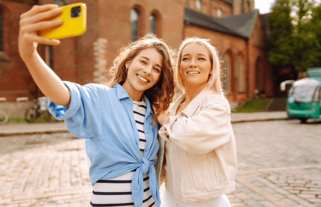 Two women smiling in a selfie with a yellow phone