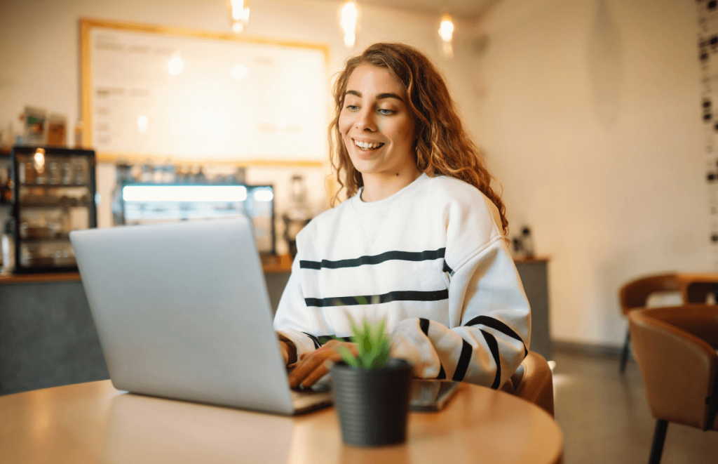 Woman smiling at her laptop in a coffee shop