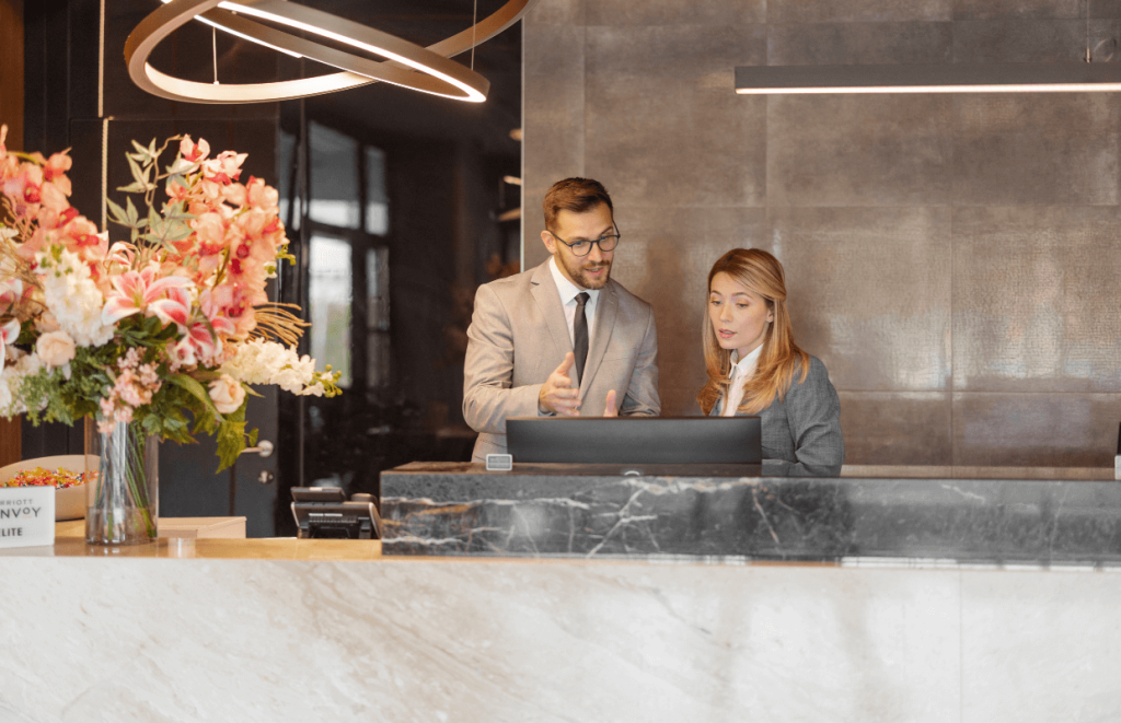 Leadership Skills: Two hotel workers talking in front of a computer