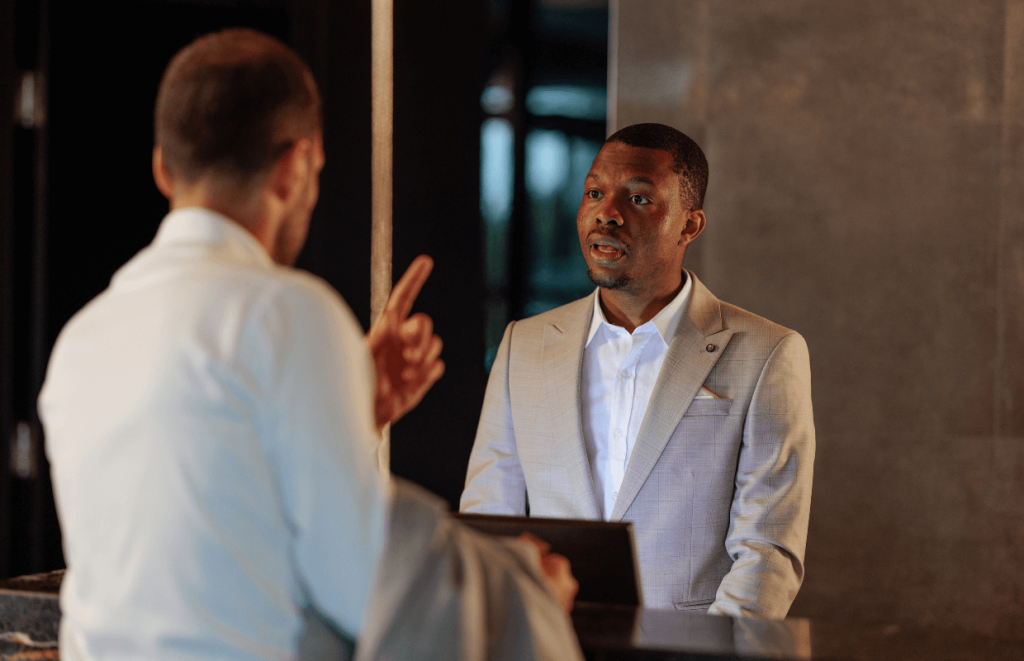 How to Handle Customer Comaplints - A male hotel worker listening to a guest at reception