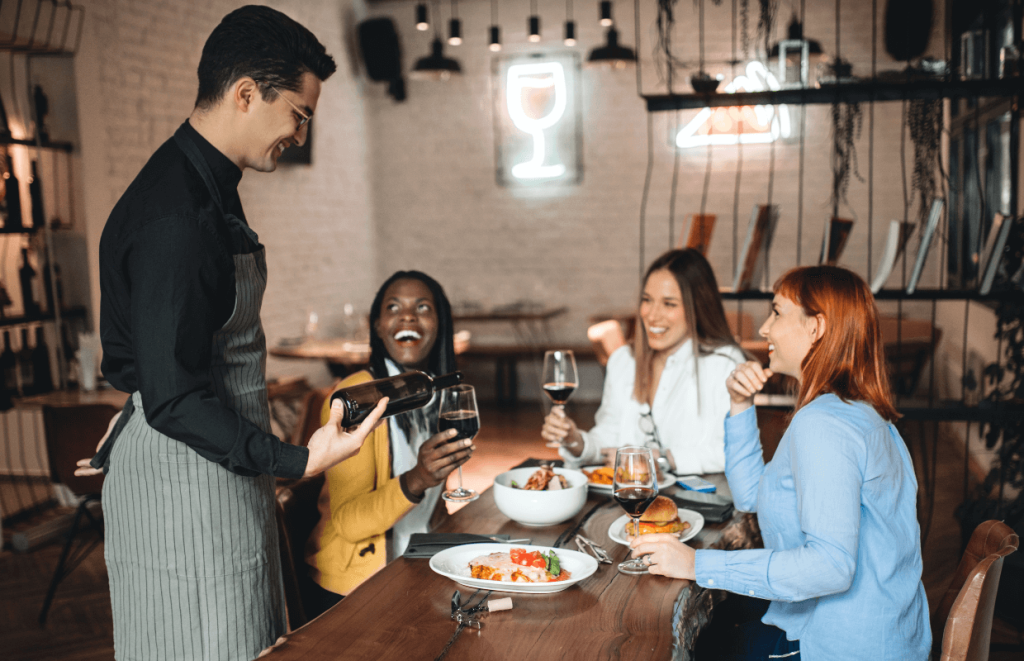 How to Handle Customer Complaints - Waiter pouring wine for a happy group of diners