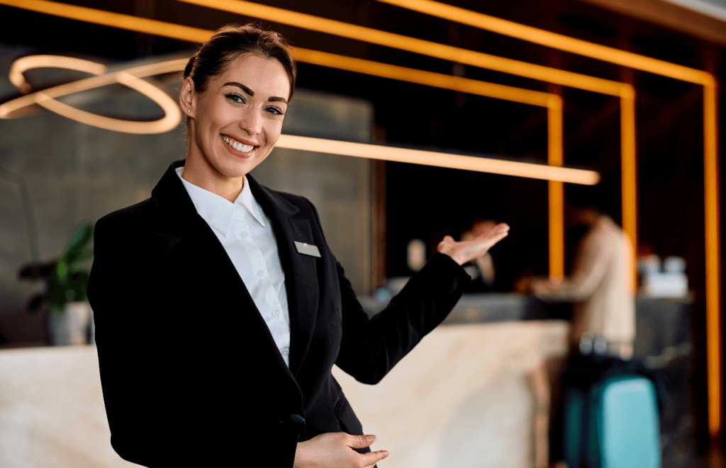 Hotel receptionist holding her palm out in a welcoming way.