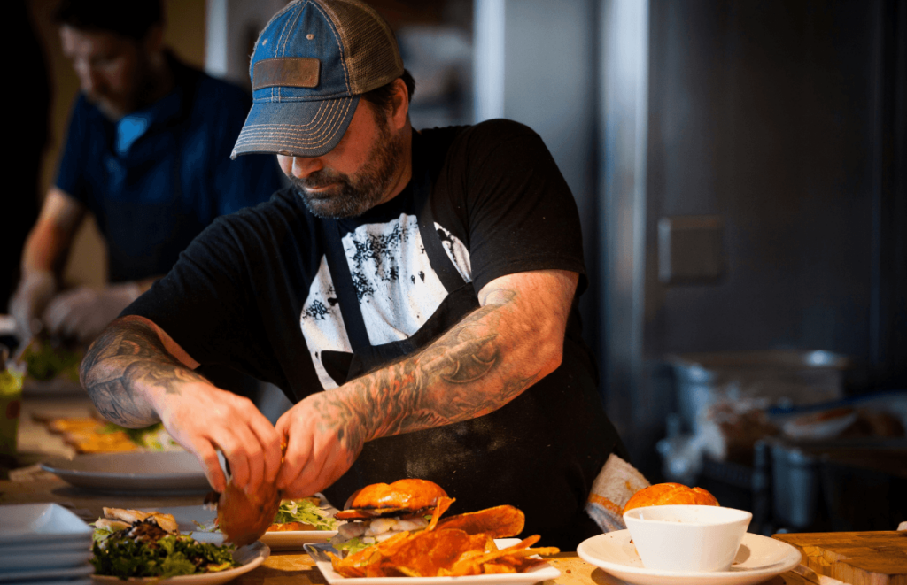 A grill chef in an apron preparing burgers