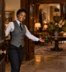 Female concierge holding open hotel door and welcoming you inside
