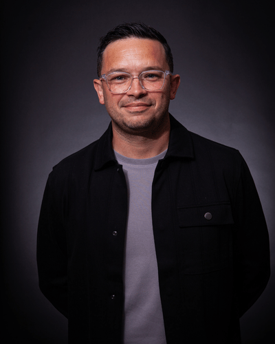 Portrait of Andy Sicnlir wearing glasses, a grey t-shirt and dark jacket