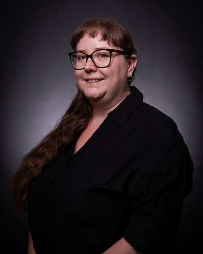 Portrait photo of Sophie Uglow smiling at the camera, dressed in a black top